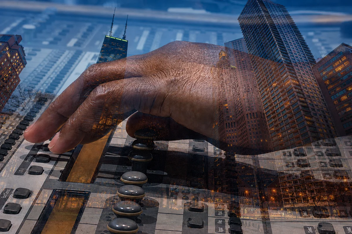 A photographic double exposure blends a Black hand adjusting an audio mixing console with Chicago high-rises glowing at dusk.