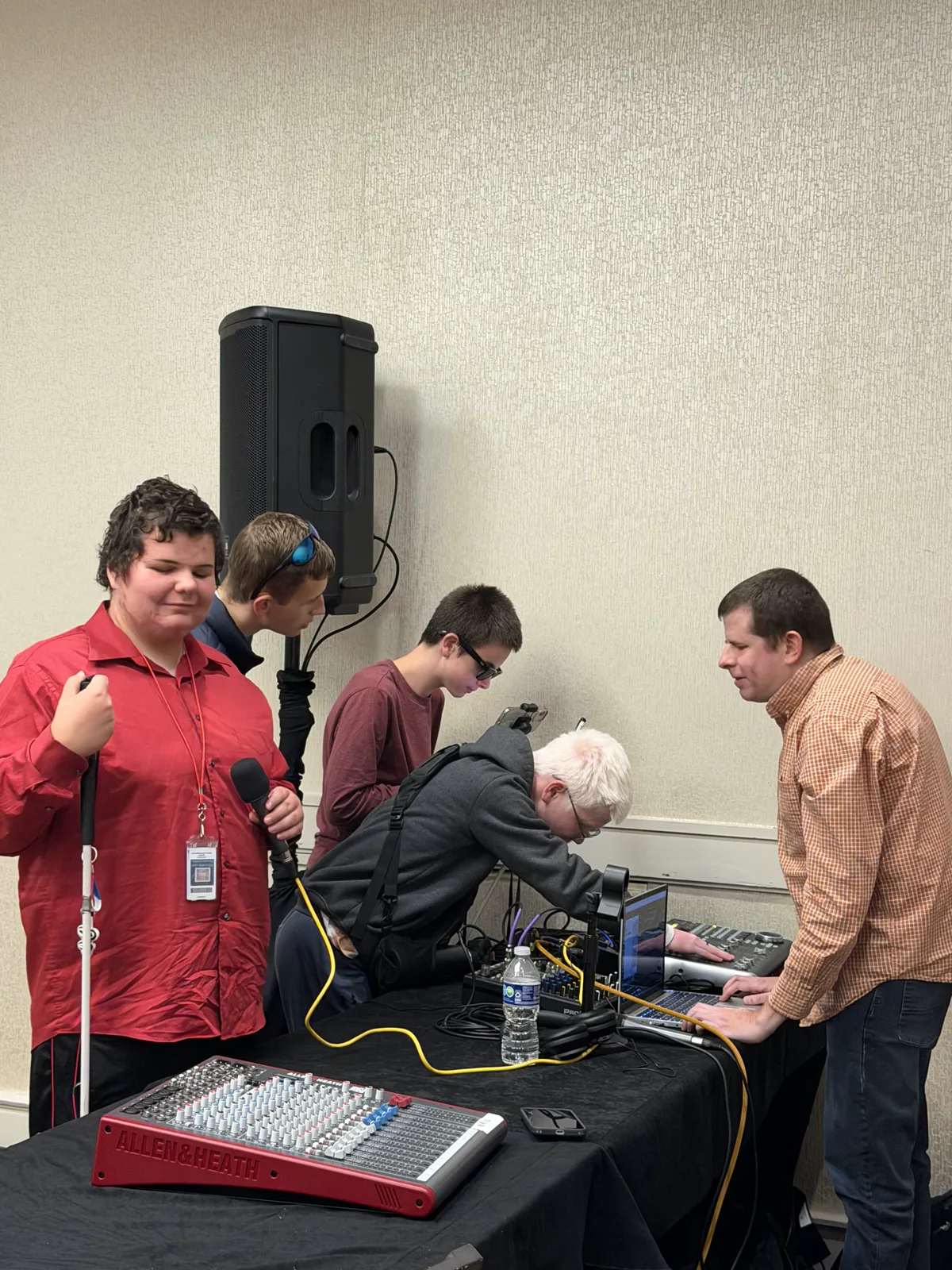 Derek Lane stands beside blind participants exploring REAPER audio production equipment.