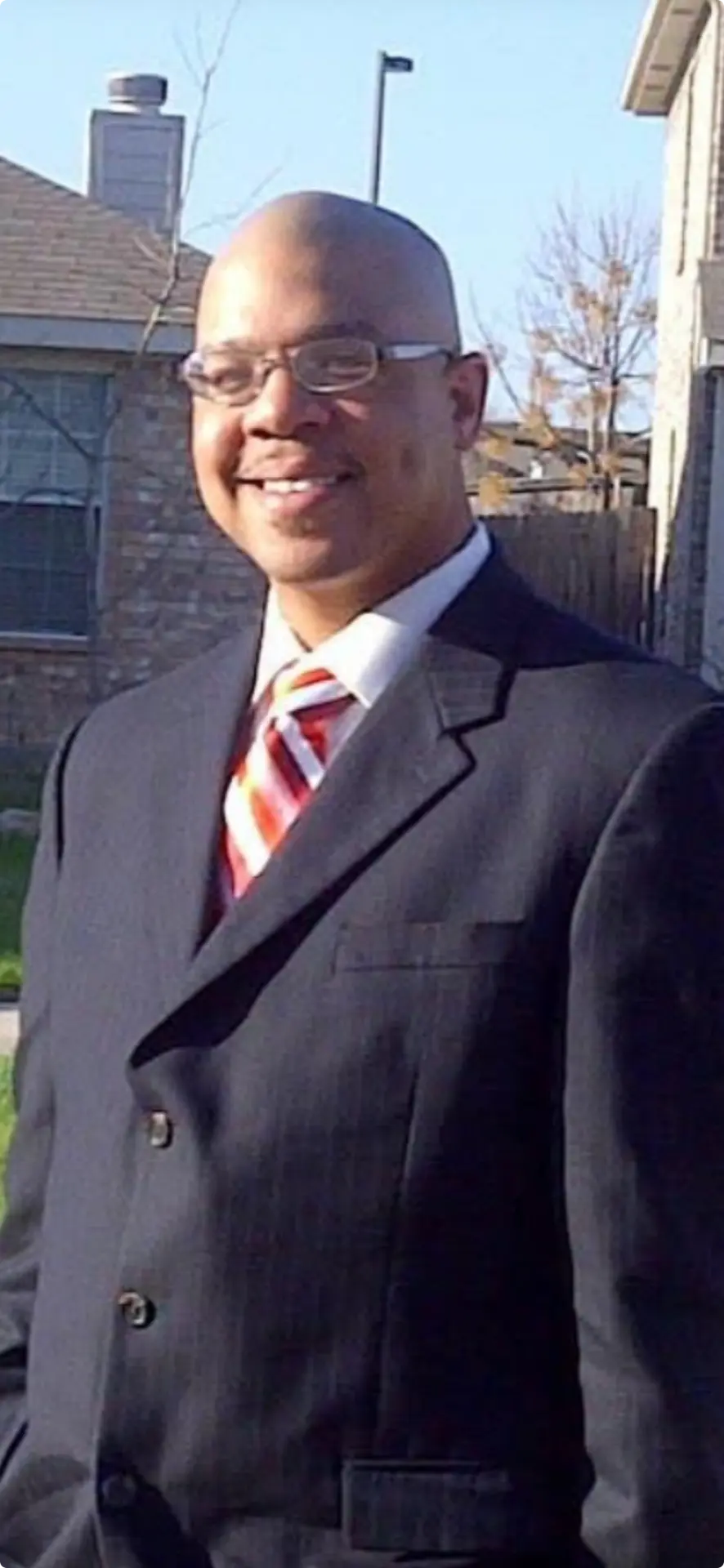 Portrait of D'Artagnan Partee smiling and wearing a dark suit with a striped tie