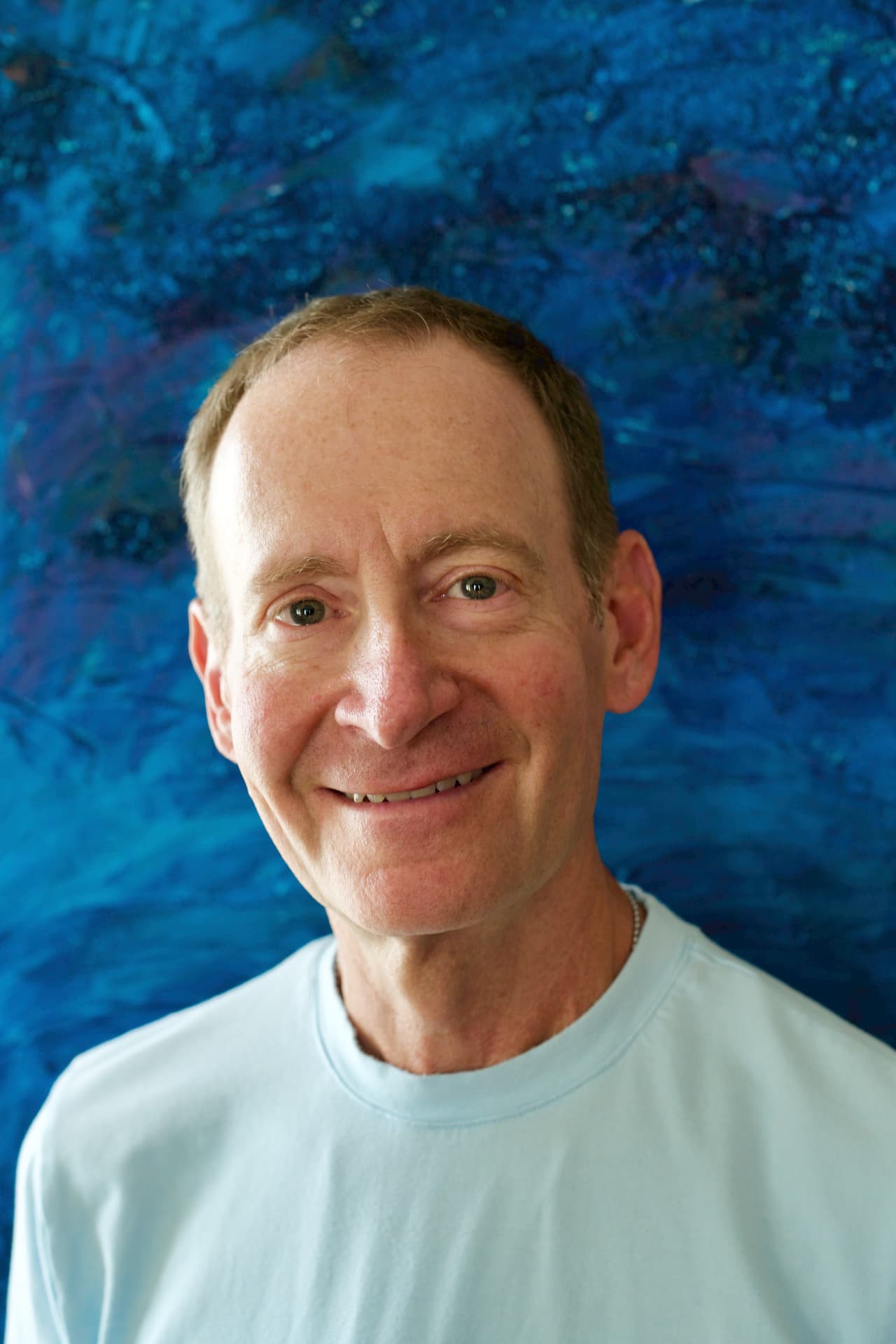 Portrait of Michael Stone smiling in front of a blue abstract background