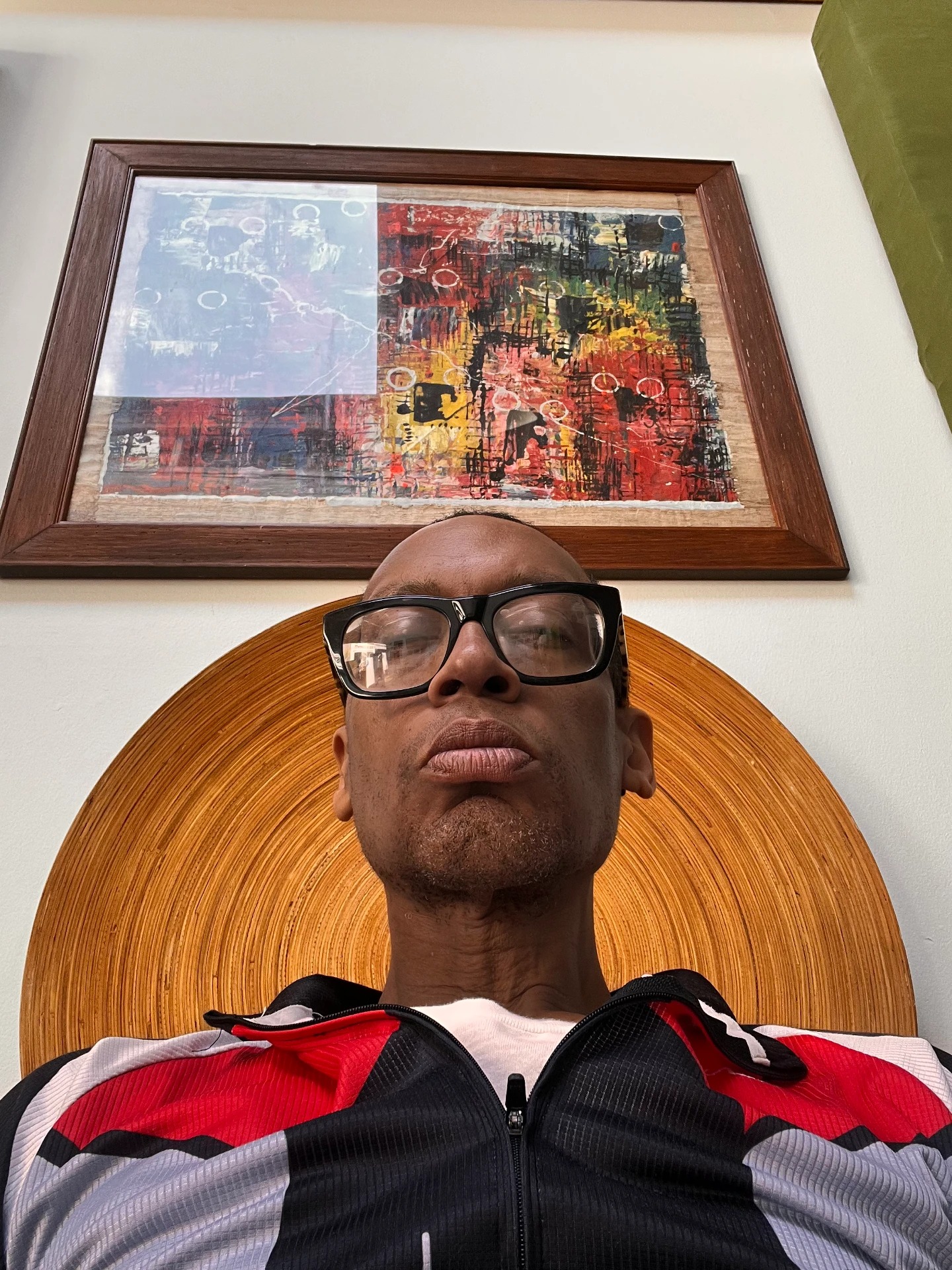 Portrait of Thomas White wearing black glasses beneath framed artwork